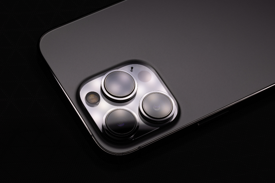 The back of a smartphone with three camera lenses on a dark surface